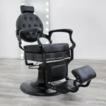 barber chair for sale Blackout barber chair in matte black vinyl with a tufted backrest, black powder-coated hydraulic base, and reclining handle.