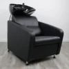 salon chair and shampoo bowl Gravity shampoo backwash unit featuring a sleek matte black fiberglass base, high-density black vinyl chair, and an adjustable tilting black ceramic bowl.