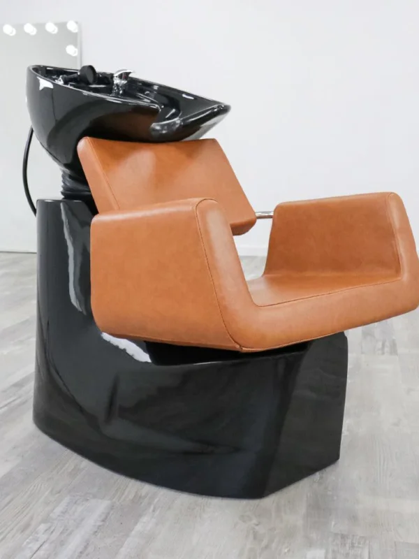 salon shampoo bowl chair Modern Illusion shampoo backwash unit featuring a sleek matte black fiberglass base, high-density black vinyl upholstery, and a deep tilting ceramic bowl.