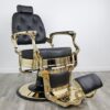 barber shop chairs Knockout Gold barber chair featuring matte black vinyl upholstery, a gold-chromed steel frame, tufted backrest buttons, and a heavy-duty hydraulic base.