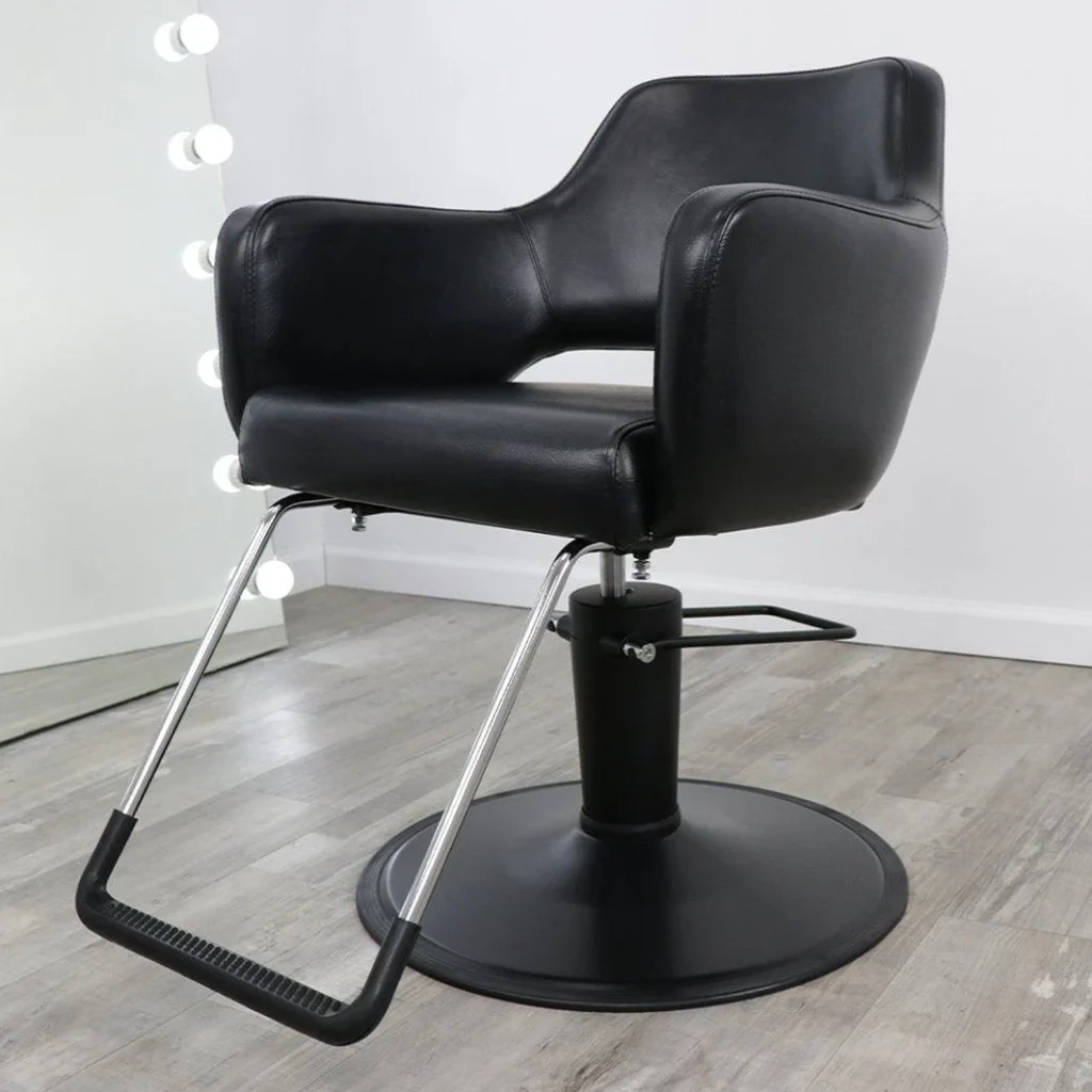 A sleek, modern salon with rows of contemporary James Barber Shop chairs arranged in a well-lit, minimalist setting. The chairs feature clean, angular lines and plush, leather-upholstered seats in a range of neutral tones. Soft, diffused lighting from overhead fixtures casts a warm, inviting glow, highlighting the chairs' polished chrome accents. The background showcases a simple, monochromatic wall, allowing the chairs to take center stage. The overall atmosphere conveys a sense of sophisticated refinement, perfect for an upscale salon experience.